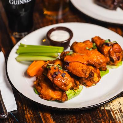 Buffalo wings served alongside celery sticks, carrots, and ranch sauce.