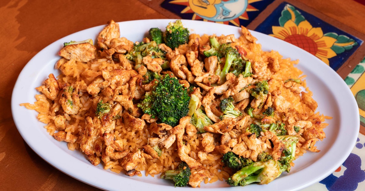 Sliced chicken breast prepared with onions on a bed of Mexican rice signature dish