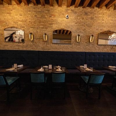 Interior, dining seating by a brick wall, tables set for dining