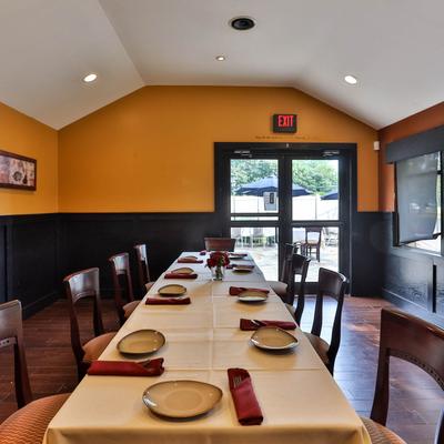 Dining room, a long white-clothed table set for many, a door leading to the patio.