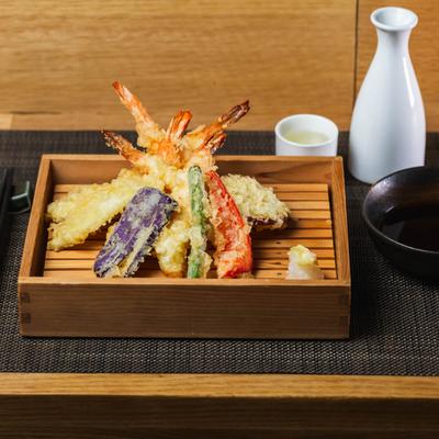 Shrimp Tempura served with a sauce for dipping and sake on the side.