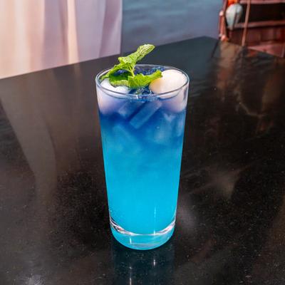 A blue-colored Mojito mocktail, garnished with mint.