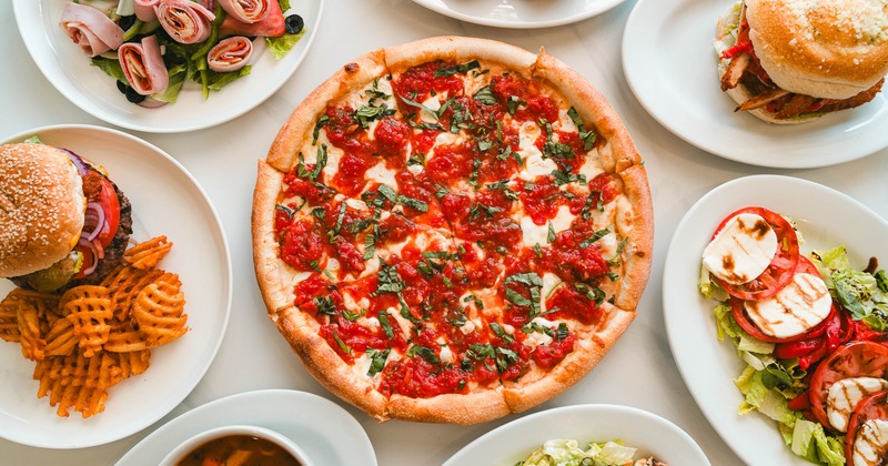 Margarita pizza served alongside various dishes, overhead view