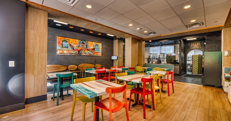 Interior of a vivid and cozy dining area with wooden tables and colorful chairs