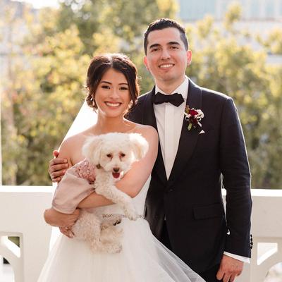 The groom embracing the bride who holds a dog.