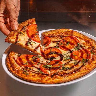 A person takes a slice from a pizza plate.