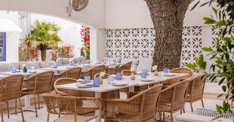 Exterior seating area with tables and woven wooden chairs