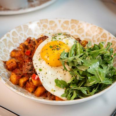 Short Rib Hash topped with a seasoned sunny-side-up egg and arugula.