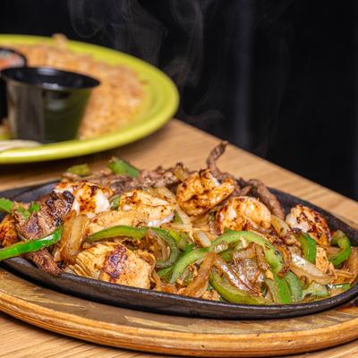 Chicken, steak, and shrimp Fajitas, with grilled onions and peppers.