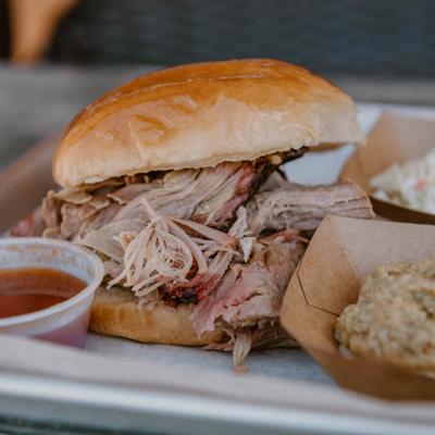 Pulled pork sandwich served with a dipping sauce and sides.