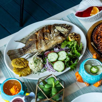Pan fried Snapper served on the table with other dishes and drinks.