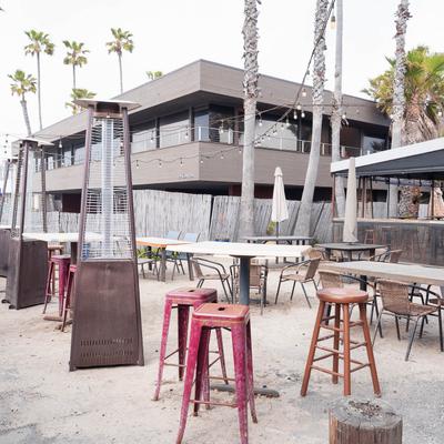 Outdoor seating area featuring tables, chairs, parasols, and patio heaters.