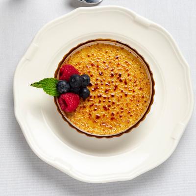 Creme Brulee garnished with blueberries, raspberries and a mint leaf.