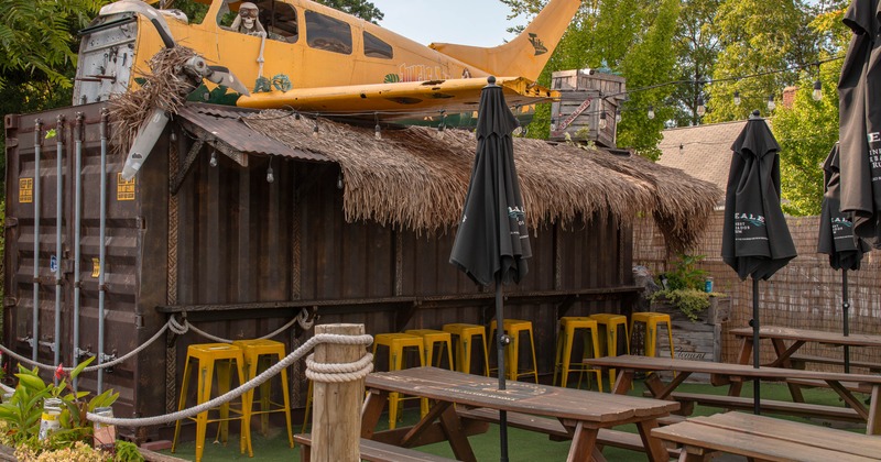 Outdoor seating area with picnic tables and a bar made from a shipping container