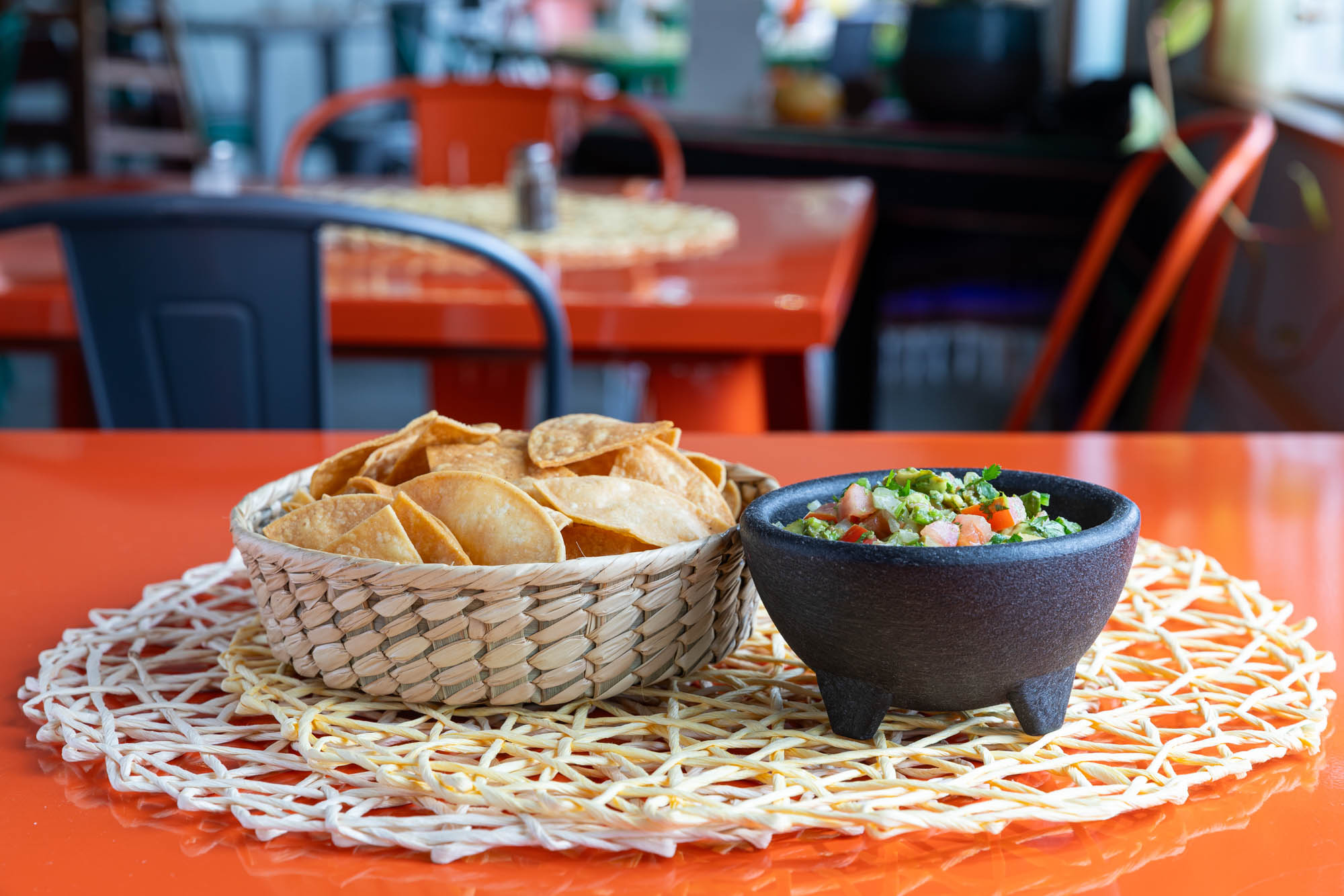 Guacamole served in a Mexican mortar with a basket of chips on the side