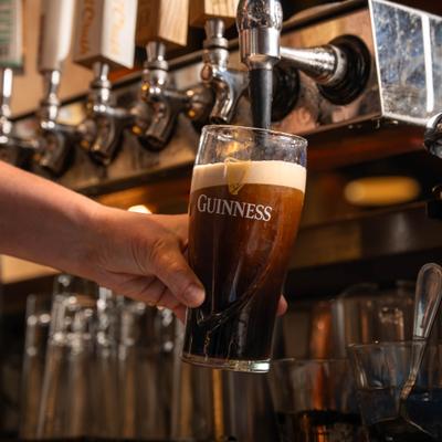 Draft stout beer being poured into a glass with creamy foam.