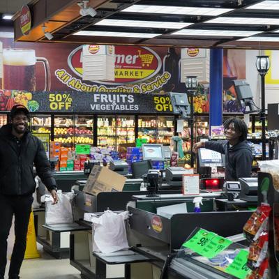 Employees smiling at the supermarket checkout area.