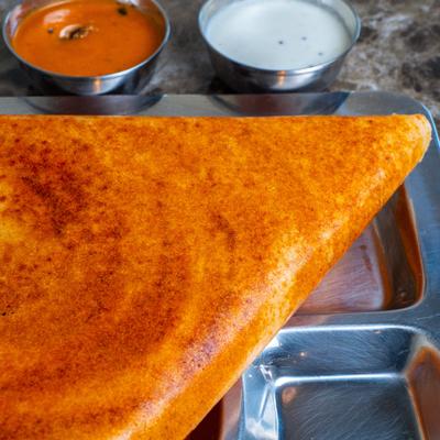Spicy dosa crepe served with coconut chutney and tomato chutney.