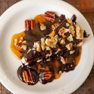 Turtle Cheesecake topped with a drizzle of chocolate, caramel sauce and pecans.