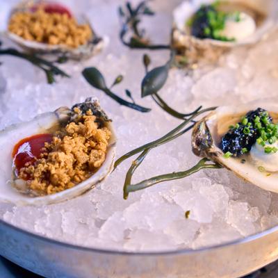 Assorted oysters on the half shell with toppings, caviar, and sauces served on ice.