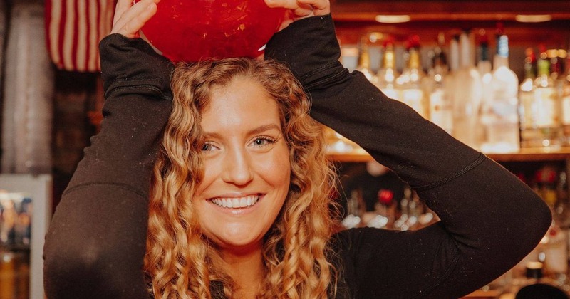 Person holding a cocktail pitcher on their head in a patriotic bar setting