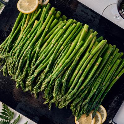 grilled asparagus with lemon, served on square cast iron pan.