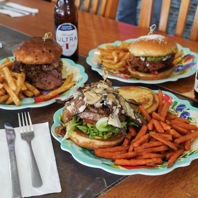 Assorted burgers with fries and a bottles of beer on a table.
