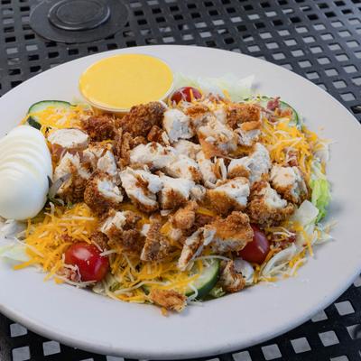 Cobb Salad with fresh vegetables, chicken, hard-boiled egg, grated cheese and a dressing.