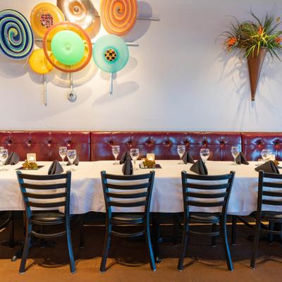 Set dining table with chairs and button tufted leather seating by a decorated wall