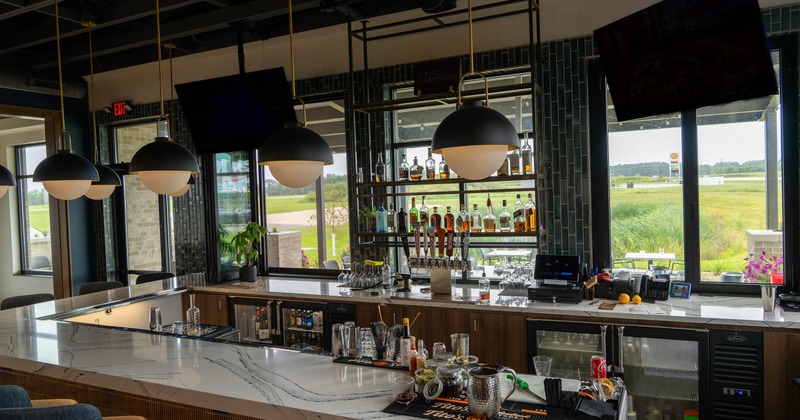 Bar area with a marble counter, liquor bottles, modern lighting, and large windows