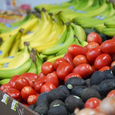 Display of fresh produce featuring tomatoes, avocados and bananas.