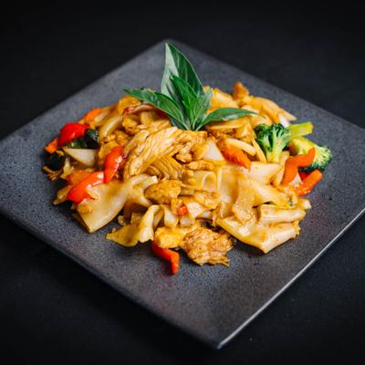 Thai drunken noodles with chicken and basil garnish.