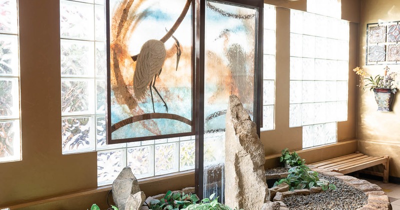 Interior, a glass fountain wall with a crane decoration surrounded with stone wall