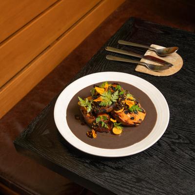 Dish of roasted sweet potatoes served on the table with cutlery.