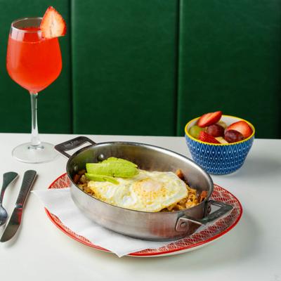 Breakfast skillet with eggs and avocado served with fresh fruit and a strawberry mimosa.