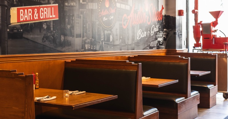 Interior - wooden booths and a wall mural reading "Austin Street Bar & Grill"