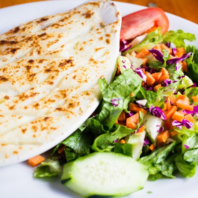 Crispy potatoes tops a dish of shepherd's pie served next to a salad of greens, carrots, cucumber and tomato
