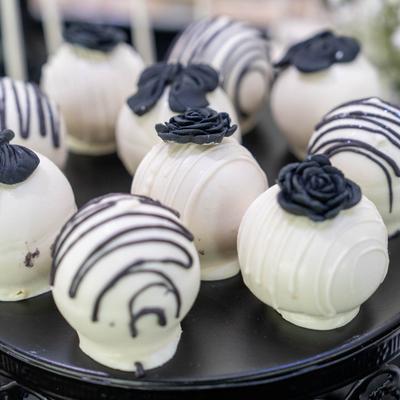 White cake pops decorated with black roses and stripes.