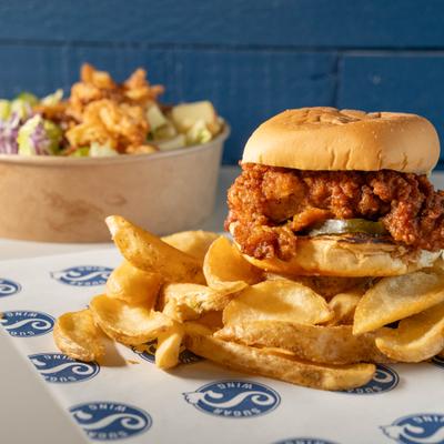 Fried chicken sandwich served alongside wedge fries.