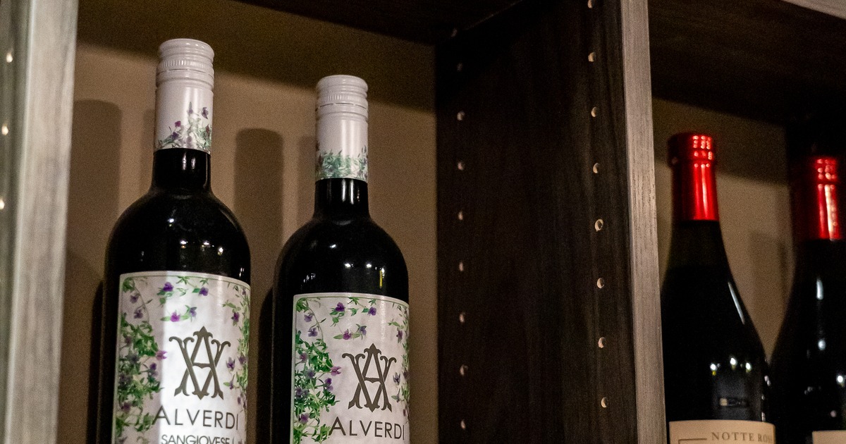 Wine bottles displayed on a wooden shelf with grapes