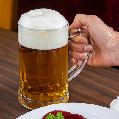 A hand holding a mug of light beer.