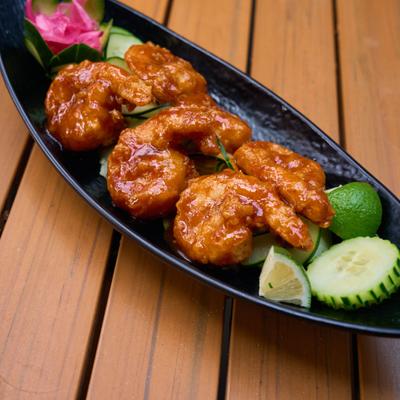 Glazed shrimp served with cucumber slices and lime wedges.