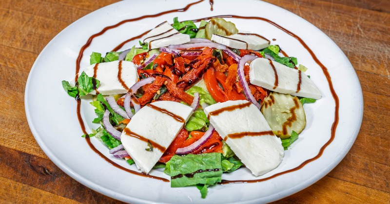 Caprese salad arranged with tomatoes, greens and mozzarella
