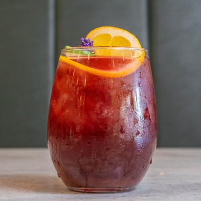 Red sangria garnished with an orange slice and a flower.