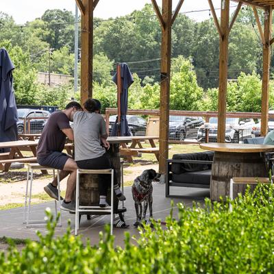 Cover seating area outside, two guests sitting at a barrel table accompanied by a dog