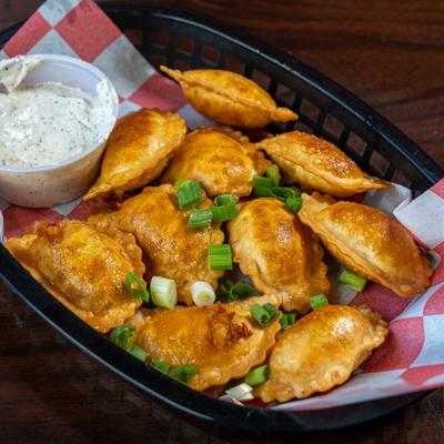 Basket of fried chicken ravioli, served with a dip.