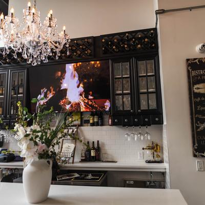 Elegant bar interior with a crystal chandelier, wine shelves, and a vase of flowers.