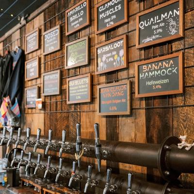 Beer taps beneath framed signs on wooden wall.