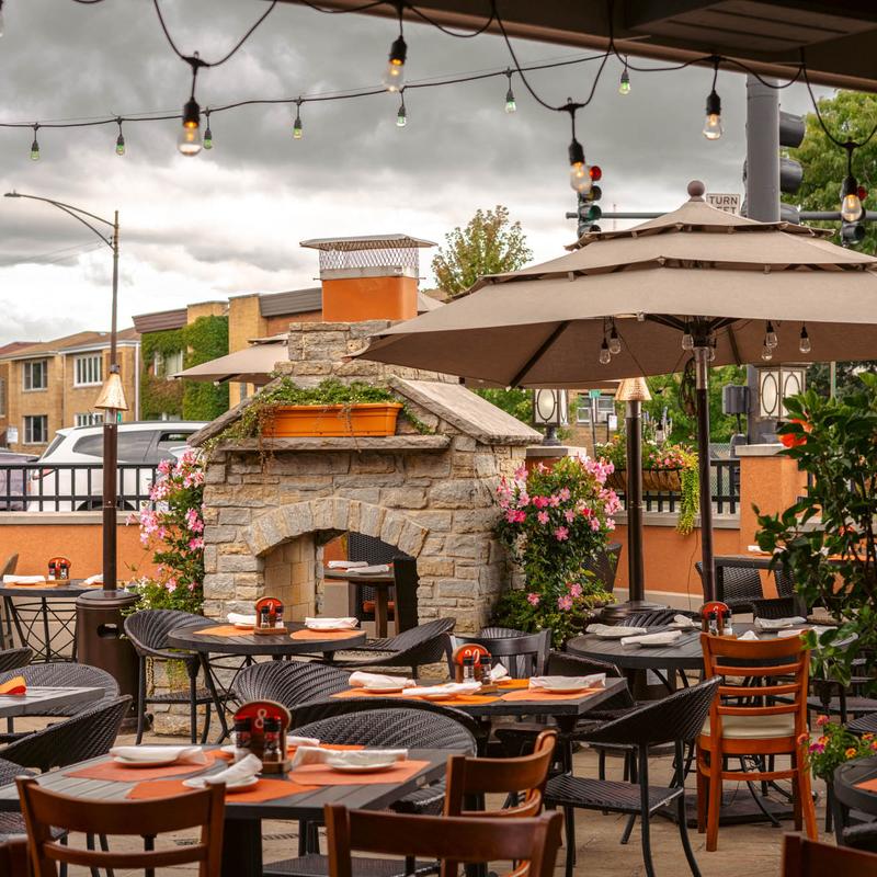 Outdoor patio seating around stone fireplace and umbrellas