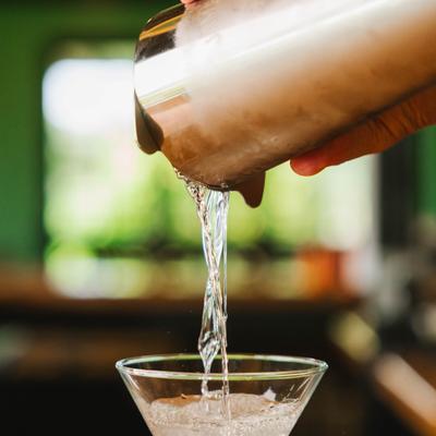 Clear cocktail being poured into a glass.
